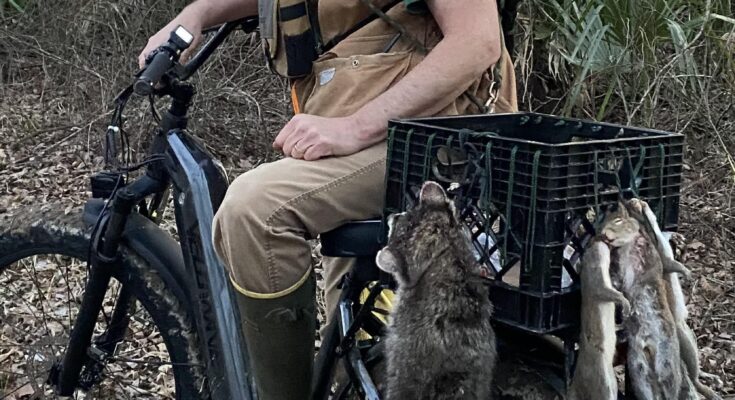 Hunter sitting on ebike with squirrels hanging from crate