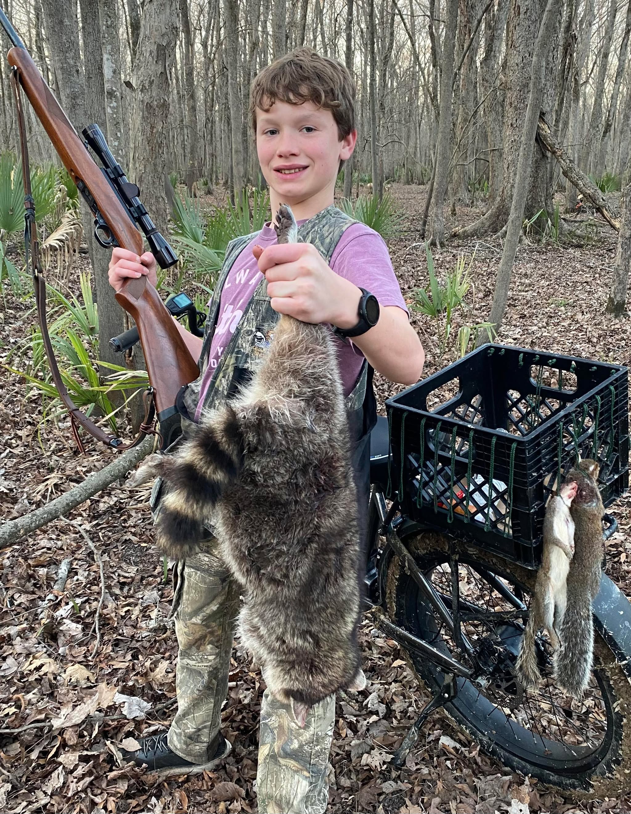 Young hunter holding squirrel with ebike in background
