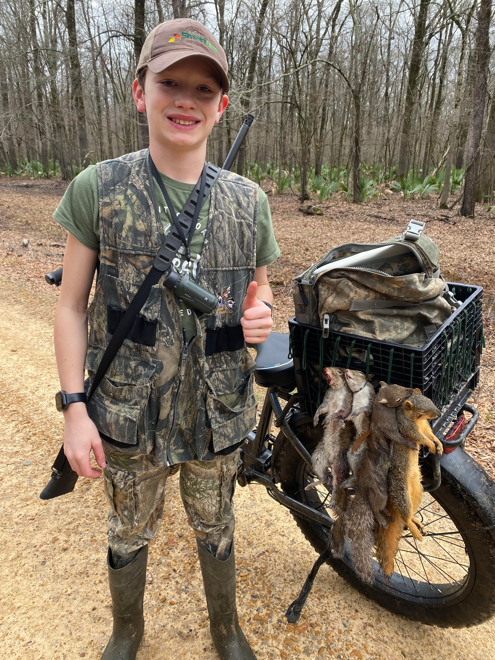Young hunter in camo with squirrels in ebike crate